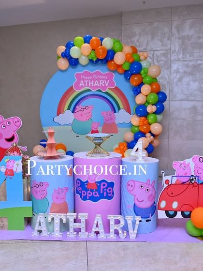 A bright and cheerful Peppa Pig theme for a 4th birthday. This setup includes a large circular backdrop with a rainbow, themed pedestals, a cutout of the iconic red car, and a large number '4'.