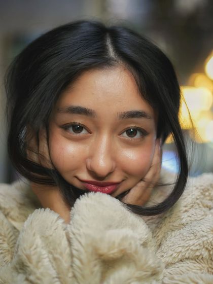 A tight close up that creates an intimate and personal feel. The focus is entirely on her expressive eyes and the soft glow of the lights around her.