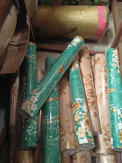 A pile of our floral wallpaper rolls, showing some of the different color options available for the same pattern. We always have plenty of stock for your projects.