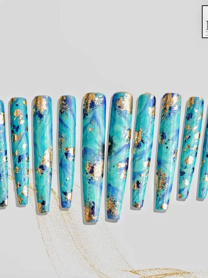 Inspired by the beauty of natural stone, this set features a turquoise marble effect with flecks of gold foil. Each nail is a unique piece of art, creating a cohesive and luxurious look on these long, elegant extensions.