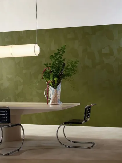 This wallcovering revives the ancient mastery of plasterwork. Each embossed groove mirrors the artisan's touch, creating a surface that is rich with history and texture, shown here in a modern olive green.