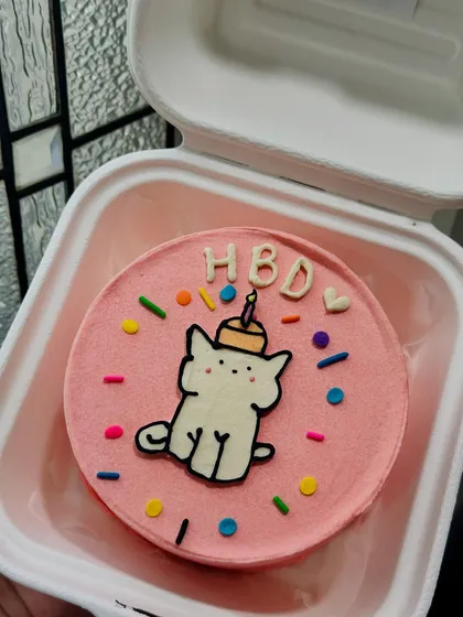 A fun and colorful birthday bento with a cat in a party hat, surrounded by sprinkles. The little 'HBD' letters add a playful touch to this celebration cake.