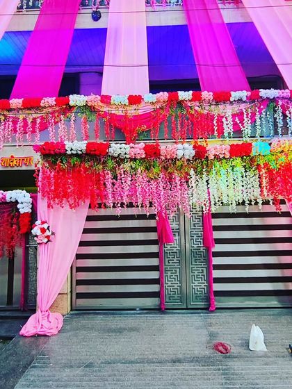 A grand entrance decorated with pink drapes and cascading white and red floral arrangements for a luxurious wedding look.