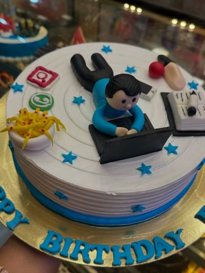 The perfect cake for a workaholic dad. This design features a fondant figure working on a laptop, surrounded by social media icons and a bowl of Maggi, humorously capturing the modern work-from-home life.