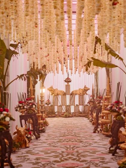 The full view of the entrance aisle, lined with traditional South Indian decor elements like banana leaves, brass cows, and hanging tuberoses.