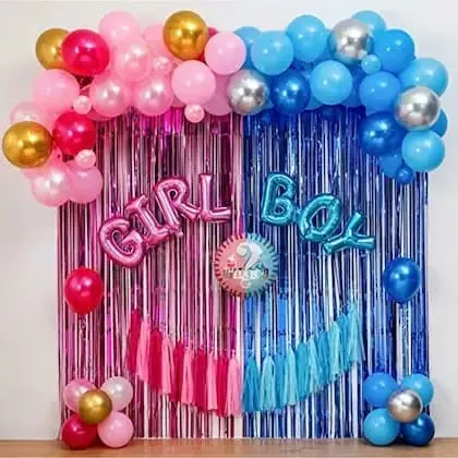 A classic gender reveal or baby shower backdrop. The decor uses a split curtain of pink and blue foil, with matching balloon arches and 'GIRL' and 'BOY' foil letters.