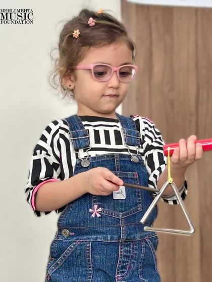 This little one is ready to play the triangle. We encourage children to explore different instruments and discover the ones they connect with the most.