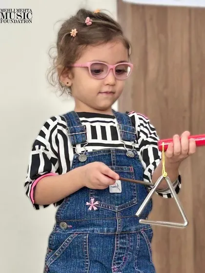 This little one is ready to play the triangle. We encourage children to explore different instruments and discover the ones they connect with the most.