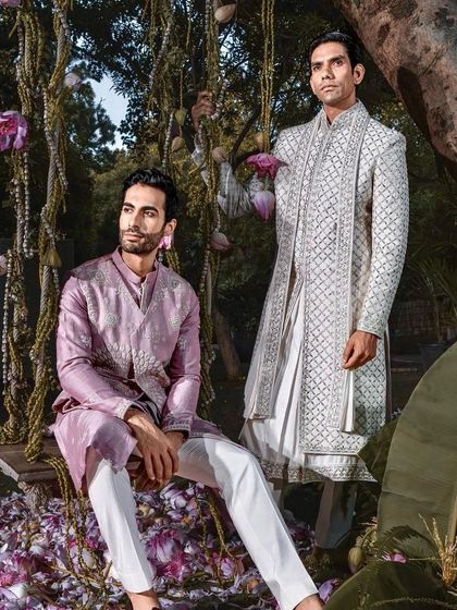 Two distinct styles for a wedding celebration. One model wears a regal white sherwani, while the other dons a contemporary mauve kurta set, showcasing our range for both the groom and his guests.