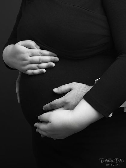 A close-up on the hands that will soon hold their baby. This shot emphasizes the shared protection and love the couple has for their unborn child.