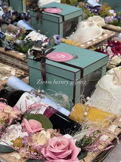 This image captures the essence of my luxury wedding hampers. A beautiful basket holds a wine bottle, gift boxes, and delicate potlis, all surrounded by floral arrangements, perfect for a wedding announcement or as a gift for the couple.
