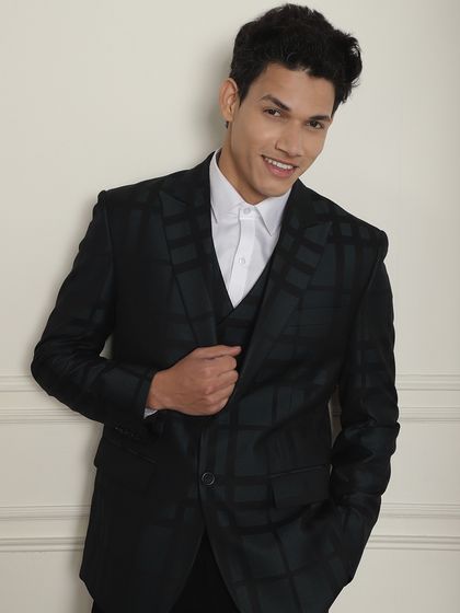 A model looks cheerful in the dark green plaid three-piece suit. It’s a sophisticated choice for the modern man.