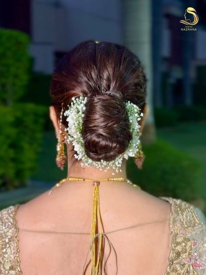 A clean, close-up shot of a sleek bridal bun wrapped in a garland of baby's breath.