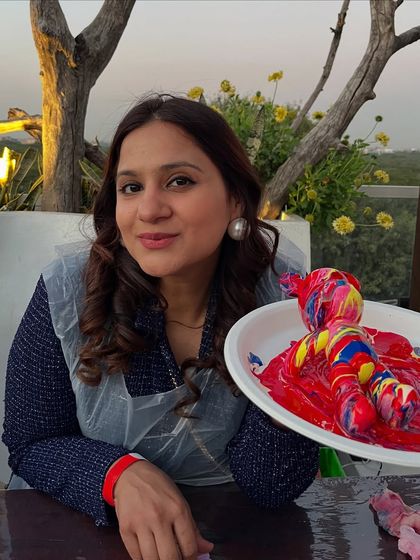 A guest smiling with her red and yellow fluid art teddy bear, made with love at a baby shower. The plastic apron keeps clothes clean while you create.