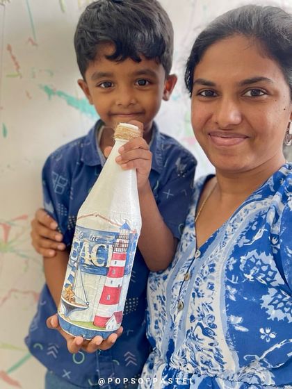 A proud mom and son duo with their finished decoupage bottle. They transformed an old ketchup bottle into a beautiful, beach-themed decorative piece.