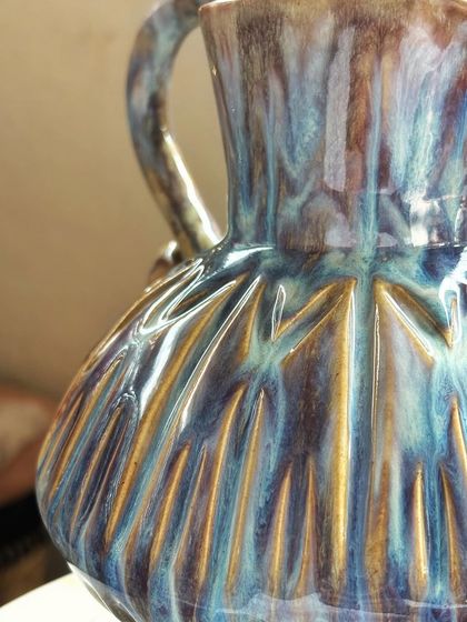 A detailed shot capturing the intricate texture and the galaxy of colors on this pitcher. The way the glazes break over the sharp edges is just mesmerizing.