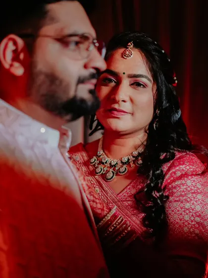 A dramatic and intimate portrait from an engagement ceremony. The warm red lighting and the couple's close embrace create a passionate and memorable image.