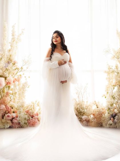 A vision in white. Framed by an abundance of soft pink and white flowers, this portrait is the epitome of romance and delicate beauty.