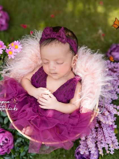 A newborn sleeping peacefully in a basket outdoors, surrounded by vibrant purple flowers. We ensure our outdoor newborn sessions are completely safe and comfortable for your little one.