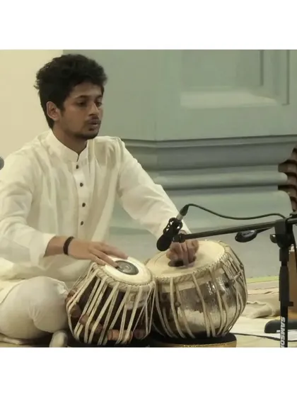 A profile shot during a solo performance, showcasing the hand movements and posture that are key to producing the rich sounds of the tabla.