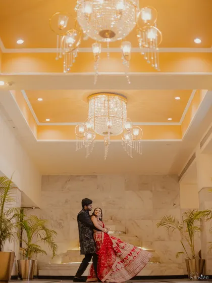 A wide-angle shot capturing the couple dancing under magnificent chandeliers. This photo highlights the grandeur of the venue and the joy of the moment.
