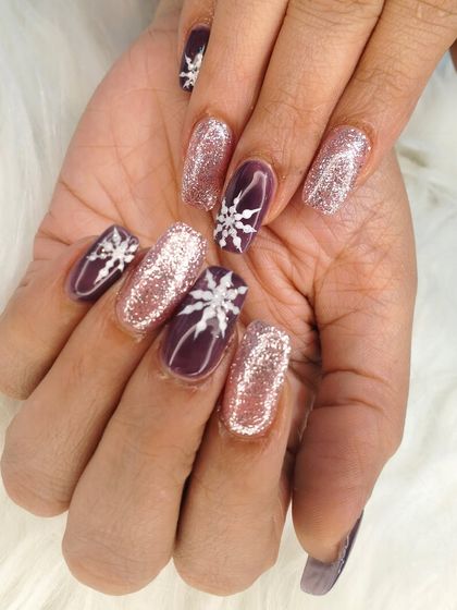 Another angle of the beautiful winter-themed manicure, showing the detail of the snowflake art and the intense sparkle of the glitter.
