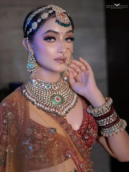 A three-quarter shot of the bride, her hand gently touching her necklace, drawing attention to the jewelry.