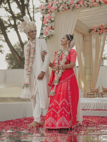 The bride and groom walk together after the ceremony, surrounded by scattered rose petals. A beautiful, cinematic shot that signifies the beginning of their journey as husband and wife.