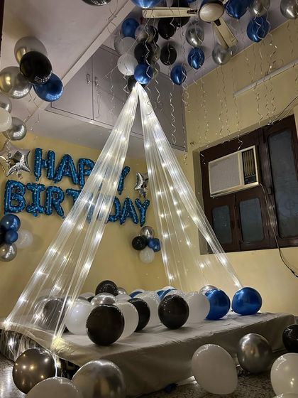 The centerpiece of this room is the bed, draped with a sheer canopy and fairy lights, and surrounded by balloons on the floor.