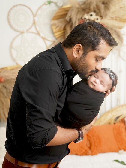 A father's gentle kiss for his newborn daughter. This tender moment is captured beautifully in our studio, highlighting the special bond between a dad and his baby girl.