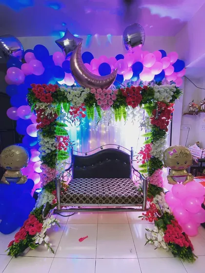 A traditional baby shower setup with a cradle decorated with fresh flowers and balloons, perfect for a home celebration.