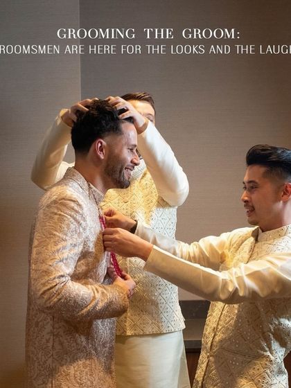 Grooming the groom with his best men. This candid shot captures the fun and camaraderie of getting ready. The groomsmen, in coordinated cream and gold outfits, help the groom with his final touches, showcasing how we style the entire groom's party for a cohesive look.