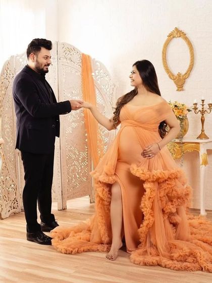 A romantic couple's shot featuring the peach ruffled gown. The elegant indoor setting complements the dress perfectly, creating a timeless and classic portrait.