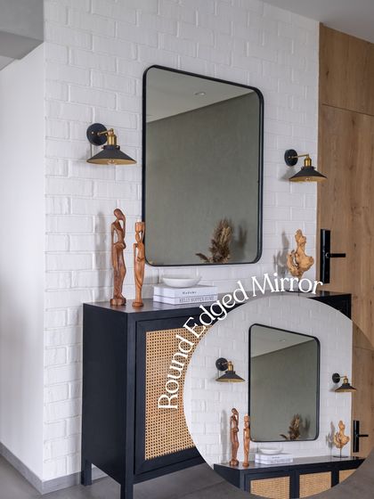 A round-edged mirror is paired with a cane-fronted console and industrial-style wall sconces. This entryway vignette demonstrates how I mix different styles and materials to create a welcoming and personalized first impression.