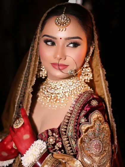 A stunning bridal look captured in dramatic lighting. The focus is on her sharp, winged eyeliner and the heavy polki jewelry, creating a regal and powerful image.