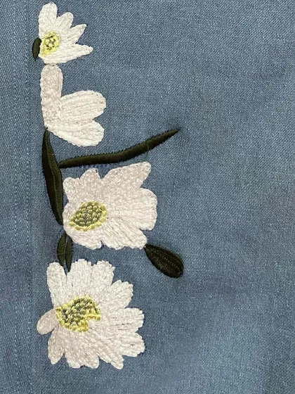 A detailed view of the machine embroidery on a pair of custom jeans. The tight, clean stitching creates a beautiful and durable floral design.