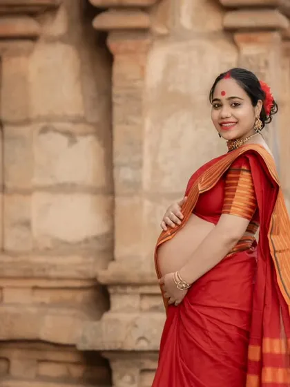 A classic three-quarter portrait of the mother-to-be, showcasing her baby bump and the beautiful details of her traditional attire against the temple wall.
