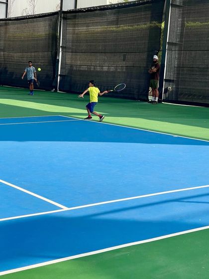A junior player hits a powerful backhand during a competitive match. We develop well-rounded players with strong skills on both wings.
