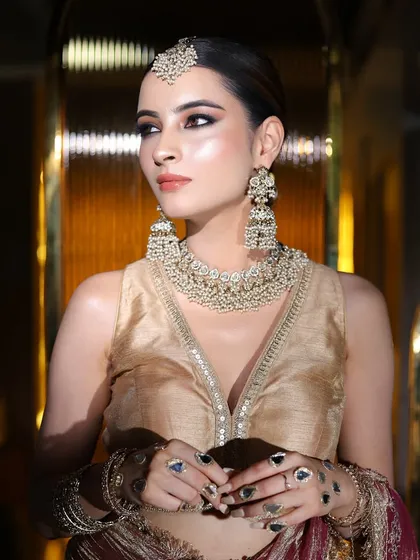 A full-length shot of a model in a gold and maroon outfit, perfect for a wedding guest or a party.