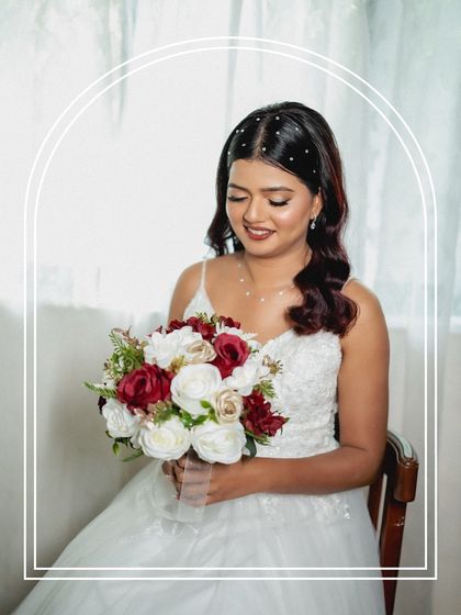 A serene bridal portrait with a decorative arch overlay. The bride is holding her bouquet, and the soft light creates a gentle and romantic mood.