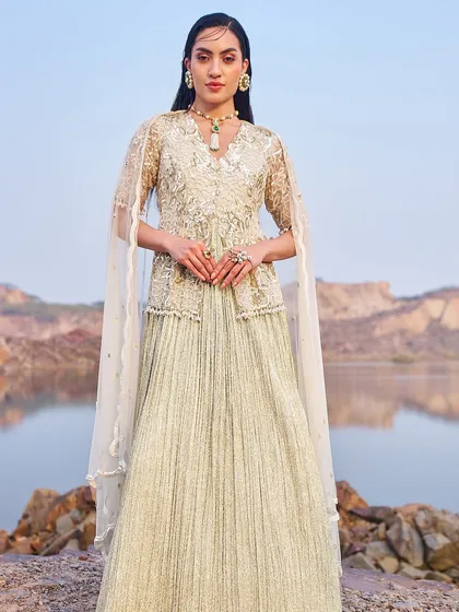 A soft, mint-green lehenga with a cape-style dupatta. The delicate shimmer and pleated skirt make this an elegant and modern choice for a daytime wedding event or evening reception.