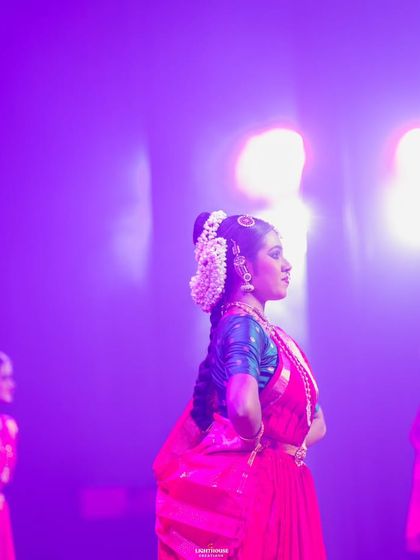 A student stands poised and ready on stage, her profile illuminated by the purple stage lights. This captures the calm focus required before beginning a piece.