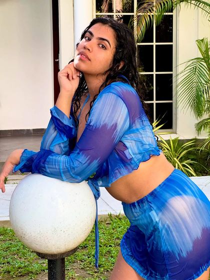 In my Moana era. A shot of me in a blue tie-dye bikini and cover-up, posing by a lamp post in a tropical resort.