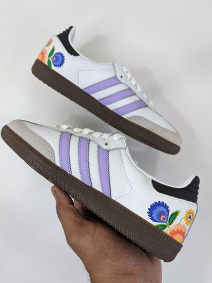 A beautiful pair of Adidas Sambas with delicate floral patterns painted on the heel, done live at a customization event.