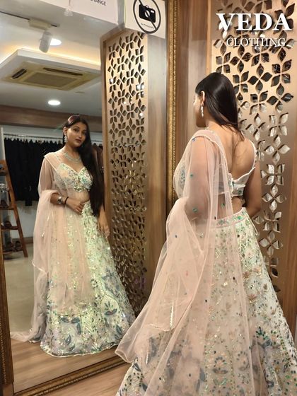 The model admires her reflection in this beautiful pastel lehenga, a perfect example of how great you can feel in a pre-loved outfit.