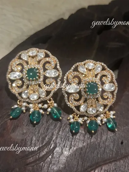 These round polki studs are adorned with delicate green bead drops. The intricate design and subtle color make them a versatile accessory for both traditional and contemporary outfits.