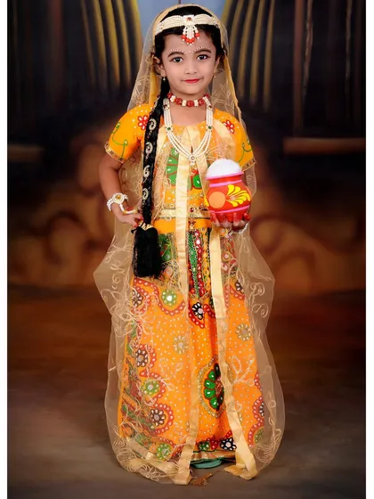 A full-length portrait of a young girl dressed as Radha for a Janmashtami shoot. The costume, jewelry, and props are all provided by the studio.