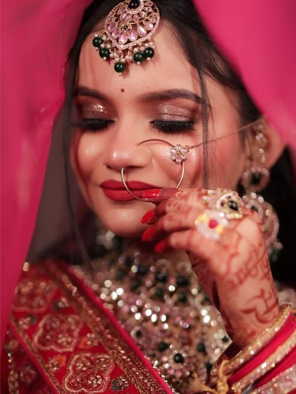 A beautiful, dreamy shot of a bride through her red veil. The focus is on her shimmery eye makeup and perfectly applied red lipstick.