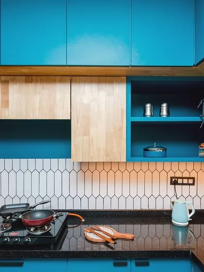 The backsplash is made of unique picket-shaped white tiles, which adds a geometric pattern and contrasts nicely with the bold blue cabinets.