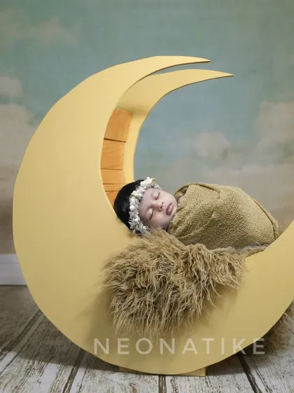 Over the moon for this little one. A simple, elegant shot of a newborn sleeping on a crescent moon prop, perfect for a timeless nursery portrait.